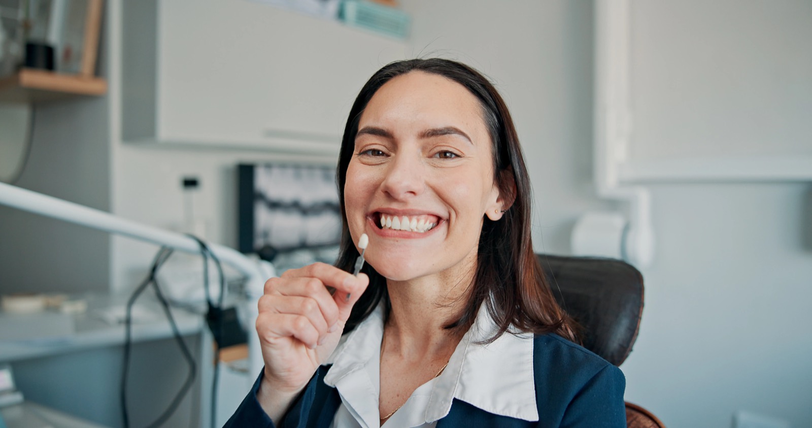 A patient's teeth being matched against a shade guide